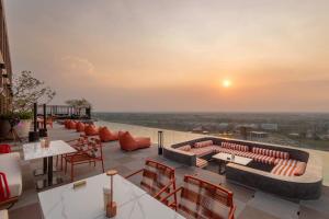 eine Dachterrasse mit Sofas und Tischen und Sonnenuntergang in der Unterkunft Centara Ayutthaya in Phra Nakhon Si Ayutthaya