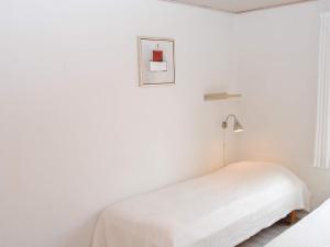 4 person holiday home in Allinge في إلينغه: غرفة نوم بيضاء فيها سرير ومصباح