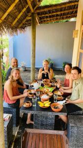 un grupo de personas sentadas alrededor de una mesa comiendo comida en Ayubowan Hiriketiya, en Dikwella