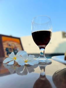 ein Glas Wein und weiße Blumen auf dem Tisch in der Unterkunft The heavens villa udaipur in Udaipur