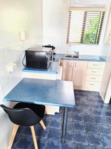 Central Studio Accommodation في غلادستون: مطبخ صغير مع طاولة وكرسي أسود