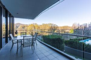 a patio with a table and chairs on a balcony at Central Located 2-Bed with Pool, Gym & Parking in Canberra