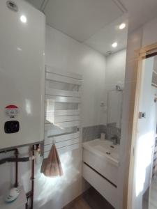 uma casa de banho branca com um lavatório e um espelho em Petit gîte bleu 