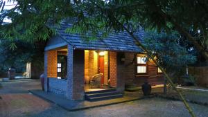 a small brick house with a cat sitting in front of it at Clayfingers Art Cottage in Trichūr
