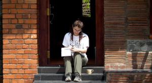 a woman sitting on steps looking at her cell phone at Clayfingers Art Cottage in Trichūr
