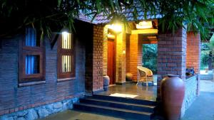 a brick house with stairs leading to a porch at Clayfingers Art Cottage in Trichūr