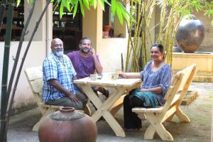 a group of three people sitting at a table at Clayfingers Art Cottage in Trichūr