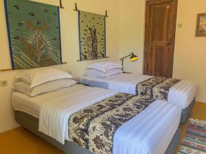 ジョグジャカルタにあるYukke Tembi Homestayのベッド2台が隣同士に設置された部屋です。