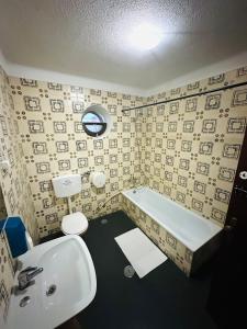 La salle de bains est pourvue d'un lavabo, d'une baignoire et de toilettes. dans l'établissement Portimao Central Holiday Guesthouse, à Portimão