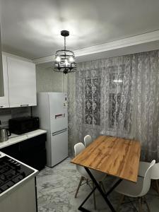 a kitchen with a wooden table and a white refrigerator at Однокомнатная квартира в центре города in Uralsk