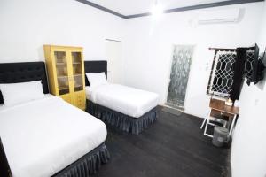 2 camas en una habitación con paredes blancas en DE Homestay Banjarmasin en Benuaanyar