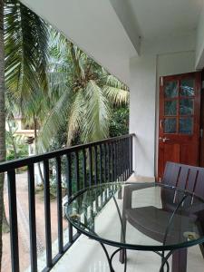 a balcony with a glass table and a palm tree at Sabinas Goa in Saligao