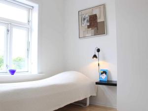 a white bedroom with a bed and a window at 6 person holiday home in Svaneke in Svaneke