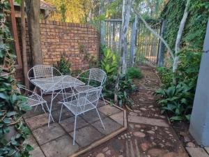 a patio with a table and chairs and a fence at Cottage by the Woods in Pretoria