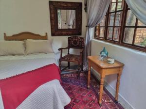 a bedroom with a bed and a table and a chair at Cottage by the Woods in Pretoria