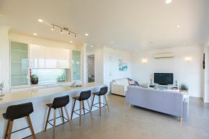 a kitchen and living room with a couch and chairs at Shearwaters Apartment Waterfront Accomodation in Penneshaw