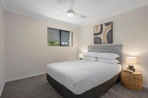 a white bedroom with a bed and a window at Comfy 2-Bedroom Family Apartment with Free Parking in Brisbane
