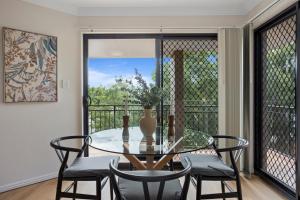 een eetkamer met een glazen tafel en stoelen bij Comfy 2-Bedroom Family Apartment with Free Parking in Brisbane