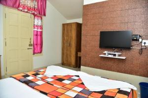 a bedroom with a bed and a flat screen tv at Coorg Lotus Villa in Madikeri