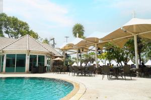 a swimming pool with tables and chairs and umbrellas at Pattaya Discovery Beach Hotel - SHA Extra Plus in Pattaya Central