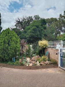 a garden with a white fence and trees at B@home in Bloemfontein