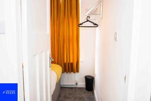 a bedroom with an orange curtain and a window at 2ndHomeStays- Stoke-on-Trent-A Serene 3 Bed House with a Garden View-Suitable for Contractors-Relocation Families-Group of Friends-Sleeps 6 - 16 mins to J15 M6 and 36 mins to Alton Towers Resort in Stoke on Trent +33 photos
