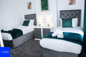 2 letti in una camera con verde e bianco di 2ndHomeStays-3 Bedroom House - Sleeps 6 - City Centre -Stoke-on-Trent a Stoke on Trent