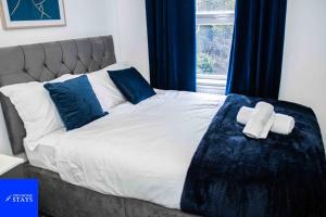 a bed with blue and white sheets and blue pillows at 2ndHomeStays- Stoke-on-Trent-A Serene 3 Bed House with a Garden View-Suitable for Contractors-Relocation Families-Group of Friends-Sleeps 6 - 16 mins to J15 M6 and 36 mins to Alton Towers Resort in Stoke on Trent