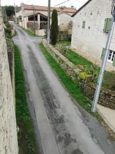 an empty road next to a stone building at Le petit Migault in La Creche
