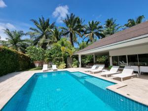 a swimming pool with lounge chairs and a house at Baan Lalle in Ao Nang Beach
