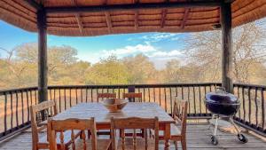 a table and chairs on a deck with a grill at Walking Tall Private Bush Retreat in Marloth Park