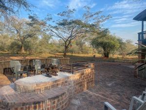 una hoguera de ladrillo en un patio con sillas en Walking Tall Private Bush Retreat en Marloth Park