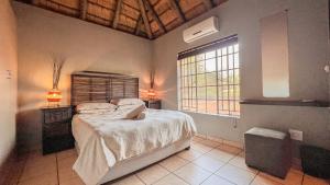 a bedroom with a large bed and a window at Walking Tall Private Bush Retreat in Marloth Park