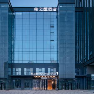 een hoog glazen gebouw met een bord erop bij Zhengzhou The Grand House in Zhengzhou