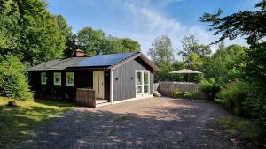 a small house with a solar roof on a driveway at A Cozy Retreat Close to Lake in Hjärnarp