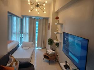 sala de estar con TV de pantalla plana grande en Newpointe suite, en Manila