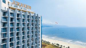 a hotel on the beach with a kite in the sky at Awaken Da Nang Hotel in Danang