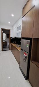La cuisine est équipée d'un réfrigérateur en acier inoxydable et de placards en bois. dans l'établissement Glory Hotel Apartment Hải Phòng, à Hai Phong