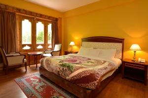 a bedroom with a bed and a chair and windows at Tiger's Nest Resort - Best Resort In Paro in Paro