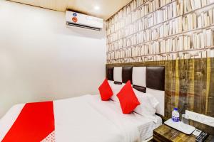 1 dormitorio con cama blanca y almohadas rojas en OYO Flagship Hotel Qubic, en Bombay