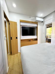 a bedroom with a bed and a flat screen tv at Stylish Staycation near BGC w/ Home Cinema in Manila