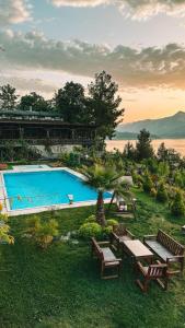 a swimming pool with tables and benches in the grass at Botanik Göl Evleri in Bucak