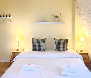 a bedroom with a large white bed with two pillows at Sandkaas Badehotel in Allinge