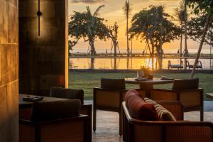 a restaurant with a view of the water and palm trees at The Meru Sanur in Sanur