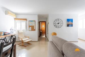 ein Wohnzimmer mit einem Sofa und einer Uhr an der Wand in der Unterkunft Apartamento Lavandula by Cadiz Time in Cádiz