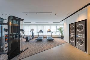 a gym with treadmills and machines in a room at UrCove by HYATT Hangzhou Riverside CBD in Hangzhou