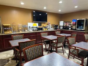 a restaurant with tables and chairs and a television at Days Inn by Wyndham Medford in Medford