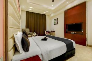 Habitación de hotel con cama grande y TV en Super Townhouse OAK Hotel C Pearls, en Nueva Delhi