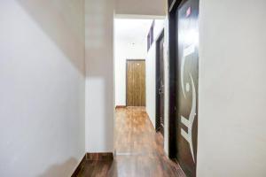 um corredor com paredes brancas e pisos de madeira e uma porta em OYO Perfect Inn em Nova Deli