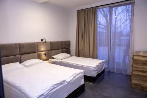2 łóżka w pokoju hotelowym z oknem w obiekcie Villa Ipanema w mieście Telawi